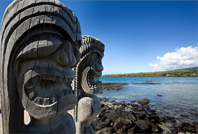 two Hawaiian wooden sculptures on the waters edge